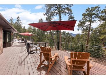Spacious deck boasts outdoor seating with an umbrella and mountain views at 7845 Armadillo Trl, Evergreen, CO 80439
