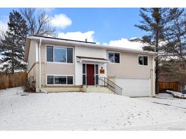 Charming two-story home features a red front door, attached garage, and manicured landscaping at 12843 W Jewell Cir, Lakewood, CO 80228