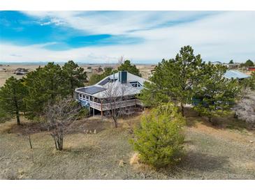Charming home featuring a wraparound porch, solar panels and surrounded by mature trees on a spacious lot at 44626 Lariat Trl, Elizabeth, CO 80107
