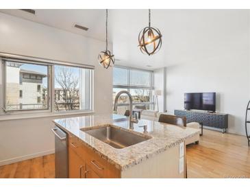 Bright kitchen featuring granite countertops, stainless steel sink, and modern pendant lighting at 2958 Syracuse St # 316, Denver, CO 80238