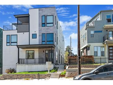 Contemporary three-story townhome featuring stone accents, covered porch, and a landscaped front yard at 1215 N Perry St, Denver, CO 80204