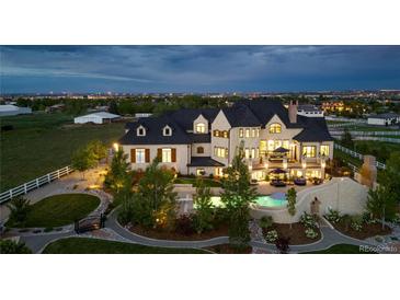 Expansive estate with sprawling lawn, pool, and elegant stone architecture, lit up against a night sky at 15355 Zuni St, Broomfield, CO 80023