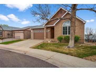 Charming brick home with a well-manicured lawn, a two-car garage and a concrete driveway at 4927 Greenwich Way, Highlands Ranch, CO 80130