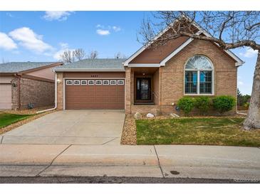 Charming brick home featuring an attached brown two-car garage and landscaped front yard at 4927 Greenwich Way, Highlands Ranch, CO 80130
