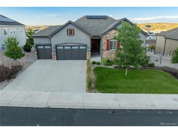 Beautiful two-story home boasts a three-car garage, red shutters, stone accents, and a well-maintained lawn at 3790 Mighty Oaks St, Castle Rock, CO 80104