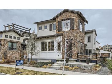 Charming two-story home with stone accents, landscaped yard, and inviting front porch seating area at 2640 S Orchard St, Lakewood, CO 80228