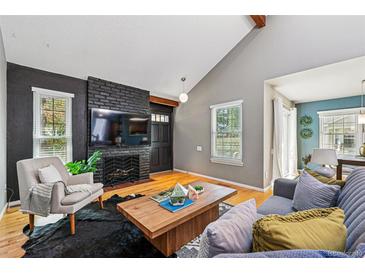 Inviting living room features a dark brick fireplace, wood floors, and large windows for plenty of natural light at 9917 Grove Way # A, Westminster, CO 80031