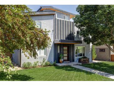 Modern two-story home with gray stucco and black metal accents, complemented by a lush green lawn and mature trees at 2048 Meade St, Denver, CO 80211