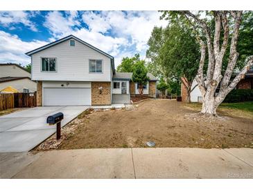 Charming home with a well-manicured lawn, long driveway, and inviting curb appeal on a partly cloudy day at 3679 S Zeno Way, Aurora, CO 80013