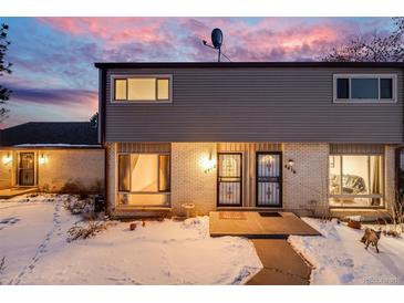 Two-story townhome with snowy front yard and illuminated entryway at dusk at 4412 W Pondview Dr, Littleton, CO 80123