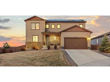 Beautiful two-story home with a manicured lawn, a two-car garage, and solar panels on the roof at sunset at 3234 Picketwire Way, Castle Rock, CO 80108