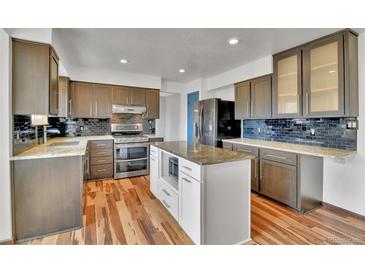 This kitchen features stainless steel appliances, light countertops, wooden floors, and a center island at 15740 Sandtrap Way, Morrison, CO 80465