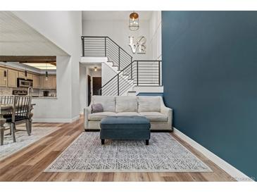 Bright living room features modern staircase, blue accent wall, and open-concept layout with stylish furniture at 14252 E Radcliff Cir, Aurora, CO 80015