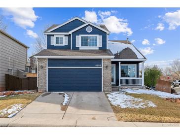 Beautiful two-story home with a navy blue exterior, a two-car garage, and a well-maintained lawn at 9790 Moss Rose Cir, Highlands Ranch, CO 80129