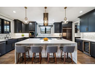 Modern kitchen with white countertops, black cabinetry, stainless appliances, and pendant lighting over a large island at 2732 S Jackson St, Denver, CO 80210
