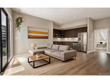 Bright living room with a comfortable sectional sofa, a modern coffee table, and stainless steel kitchen appliances at 1643 Boulder St # 211, Denver, CO 80211