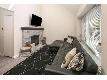 Inviting living room featuring a brick fireplace and a comfortable, modern black sectional sofa at 7978 Chase Cir # E, Arvada, CO 80003