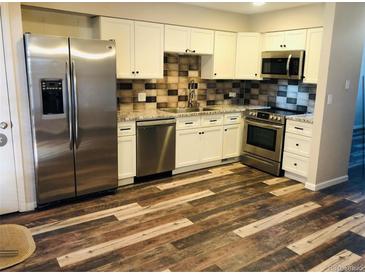 Updated kitchen features stainless steel appliances, granite countertops, and plank flooring at 2301 E Fremont Ave # W02, Centennial, CO 80122