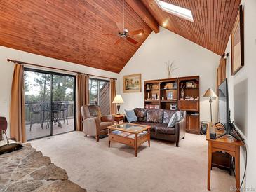 Cozy living room featuring a wood ceiling, fireplace, and access to an outdoor deck at 23485 Bluestem Dr, Golden, CO 80401