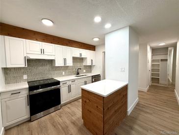 Modern kitchen with white cabinets, stainless steel appliances, and wood accents offers a sleek, contemporary design at 2500 S York St # 204, Denver, CO 80210
