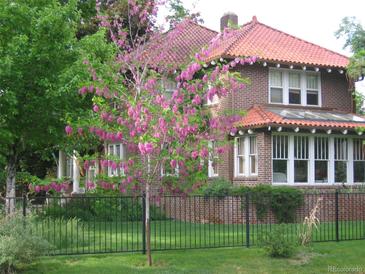 Charming brick home with a beautiful, flowering tree in the front yard at 1650 Monaco St Pkwy, Denver, CO 80220