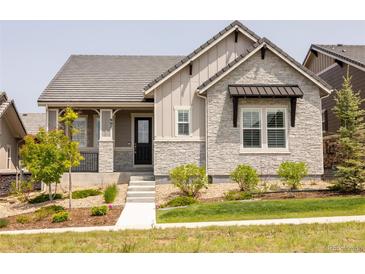 Charming home featuring stone accents, covered porch, tidy landscaping, and a well-maintained front lawn at 997 Brocade Dr, Highlands Ranch, CO 80126