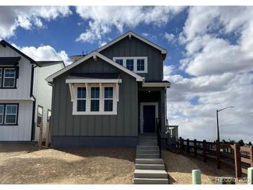 Charming two-story home with gray siding, white trim, and a welcoming front porch under a cloudy blue sky at 2025 Barnwood Dr, Brighton, CO 80601