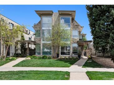 Modern, multi-story home featuring a stone facade, large windows, and a well-manicured lawn at 512 Cook St, Denver, CO 80206