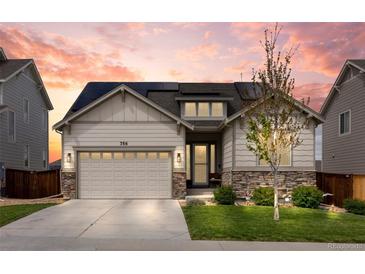 Charming home with a stone and siding exterior, solar panels, an attached garage, and a well-manicured lawn at 756 Ranchhand Dr, Berthoud, CO 80513