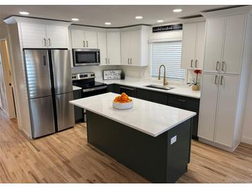 Modern kitchen featuring a large island, stainless steel appliances, two-tone cabinets, and beautiful hardwood floors at 3866 S King St, Denver, CO 80236