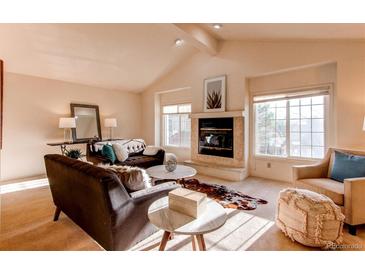Bright living room boasts vaulted ceilings, a cozy fireplace, and multiple windows providing natural light at 1530 S Quebec Way # 29, Denver, CO 80231