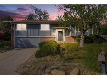Charming two-story home with grey wood siding, brick accents, and a well-manicured front yard under a colorful sunset at 2764 S Reading Ct, Denver, CO 80231