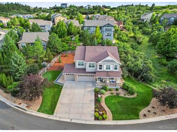 Stunning two-story home featuring a three-car garage, charming front porch, and beautifully landscaped front yard at 2384 Crestridge Dr, Castle Rock, CO 80104