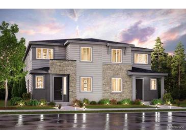 Two-story home with stone and gray siding, a well-manicured lawn, and a welcoming entrance at 14149 Deertrack Ln, Parker, CO 80134