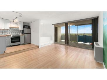 Bright living room featuring an updated kitchen with stainless steel appliances and large sliding doors to balcony at 1155 N Ash St # 1206, Denver, CO 80220
