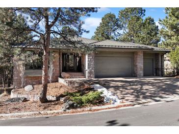 Charming stone home with mature trees, lush landscaping, and a spacious attached three car garage at 2704 Castle Brook Dr, Castle Rock, CO 80108