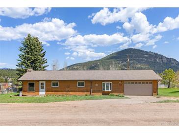 Charming single-story home with attached garage, wood facade, and mountain backdrop at 26063 Morris Ave, Conifer, CO 80433