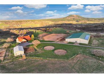 Expansive property featuring a house, horse barn, riding arena, and round pens against a backdrop of rolling hills at 5351 Tall Horse Trl, Sedalia, CO 80135