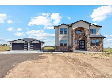 Two-story home with stone accents and a detached two-car garage at 995 Pinehurst Ct, Bennett, CO 80102