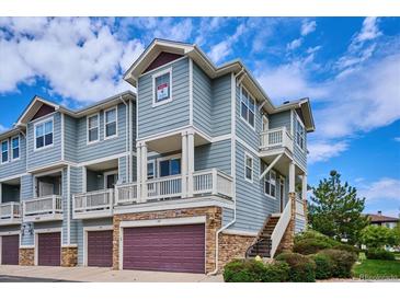 Two-story townhome with gray siding, attached garage, and balcony at 9543 Pearl Cir # 101, Parker, CO 80134