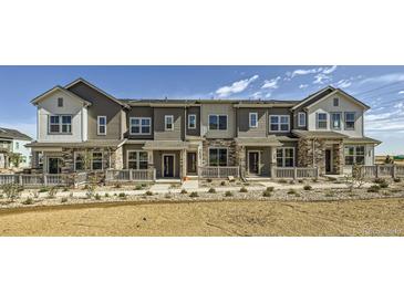 New townhome exteriors featuring a two-story design, stone accents, and manicured landscaping at 2018 S Haleyville Way, Aurora, CO 80018