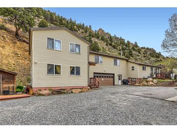 Spacious home featuring a two-car garage, gravel driveway, and a hillside backdrop at 4 Virginia St, Idaho Springs, CO 80452