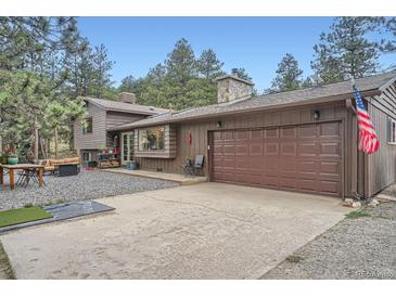 Charming exterior with a two-car garage, gravel driveway, and stone chimney at 2013 Swede Gulch Rd, Evergreen, CO 80439