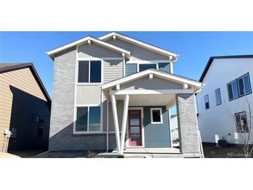 Two-story home with brick and siding, covered porch and a red front door at 2283 Serenidad St, Brighton, CO 80601