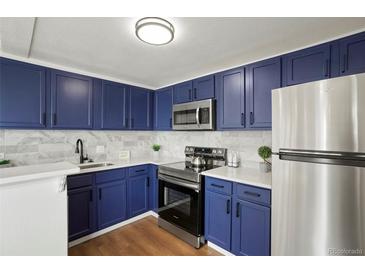 Modern kitchen boasting stainless steel appliances, sleek countertops, and dark blue cabinets at 3047 W 47Th Ave # 607, Denver, CO 80211