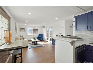 Bright and airy living room featuring wood floors, fresh white walls, and seamless kitchen access at 3047 W 47Th Ave # 607, Denver, CO 80211