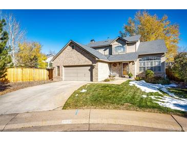 Charming two-story brick home with a well-maintained lawn and a two-car garage on a sunny day at 6454 S Nelson Way, Littleton, CO 80127