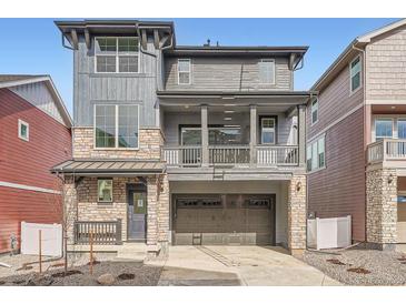 Two-story home features a stone and gray wood facade with a covered porch and two-car garage at 2058 S Haleyville Way, Aurora, CO 80018