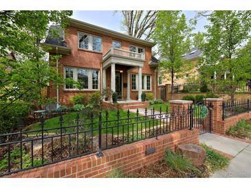 Charming two-story red brick home featuring a welcoming front porch and manicured front yard with wrought iron fence at 535 N High St, Denver, CO 80218