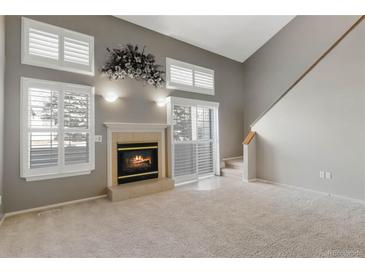 Bright living room with a cozy fireplace, neutral carpet, many windows, and access to the upper floors at 1847 S Union Blvd, Lakewood, CO 80228